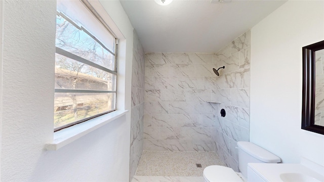 bathroom featuring a tile shower, plenty of natural light, and toilet