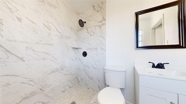 bathroom featuring tiled shower, vanity, and toilet