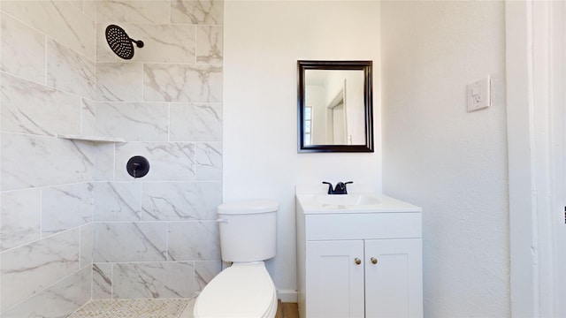 bathroom featuring vanity, toilet, and a tile shower