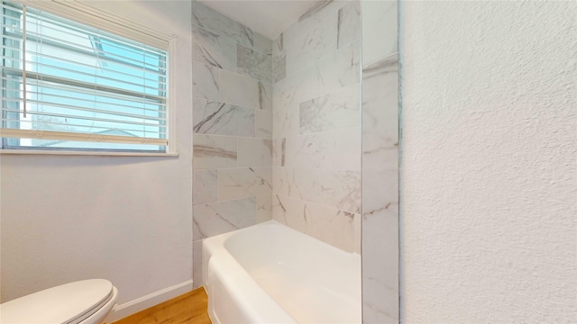 bathroom featuring toilet, tiled shower / bath combo, and hardwood / wood-style floors