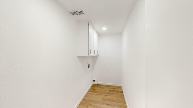 laundry area with cabinets and light wood-type flooring