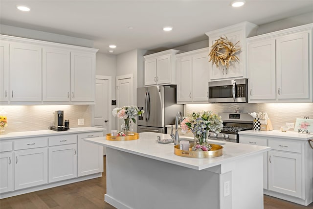 kitchen featuring dark hardwood / wood-style floors, sink, white cabinets, stainless steel appliances, and a center island with sink