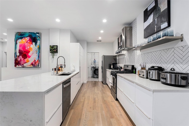 kitchen featuring sink, wall chimney exhaust hood, decorative backsplash, appliances with stainless steel finishes, and white cabinetry