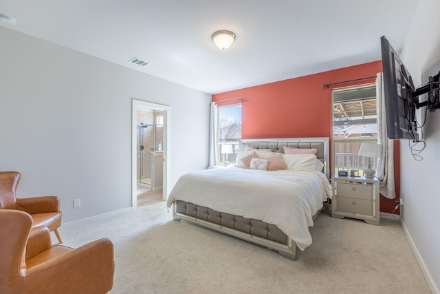 bedroom featuring light colored carpet and ensuite bath