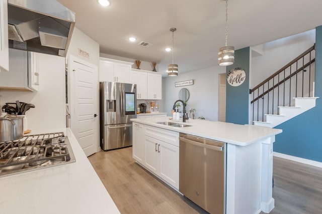 kitchen with exhaust hood, sink, white cabinets, and stainless steel appliances