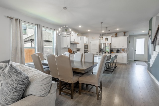 dining space with dark hardwood / wood-style floors and an inviting chandelier