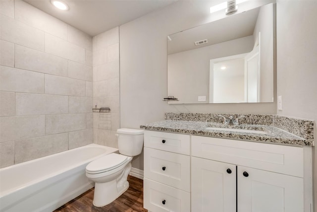 full bathroom with tiled shower / bath, vanity, wood-type flooring, and toilet