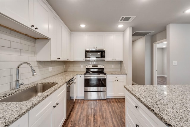 kitchen with white cabinetry, sink, light stone countertops, stainless steel appliances, and tasteful backsplash