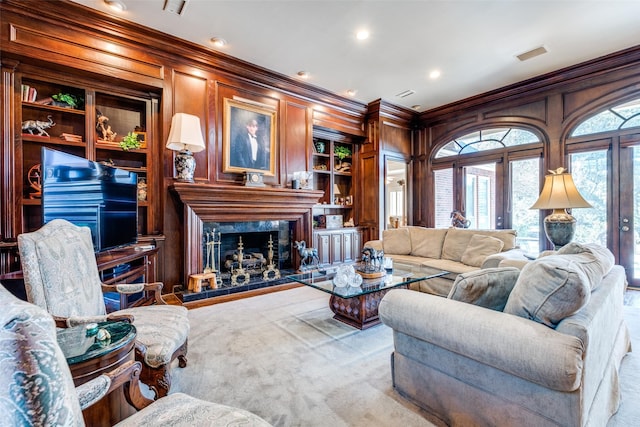 living room featuring built in shelves, wood walls, a high end fireplace, and light carpet