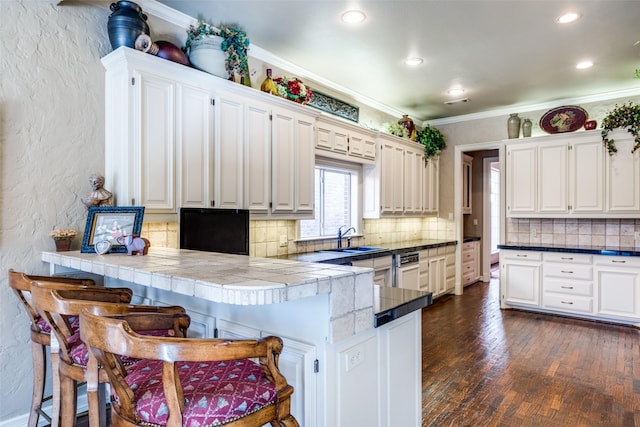 kitchen with a breakfast bar area, kitchen peninsula, and white cabinetry