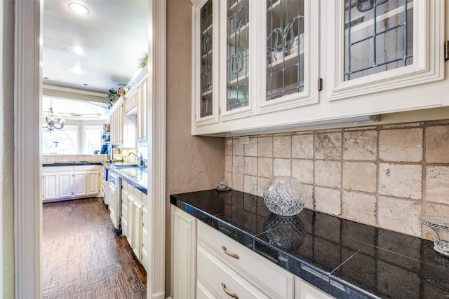 kitchen featuring dark wood-type flooring, white cabinets, sink, ornamental molding, and a notable chandelier