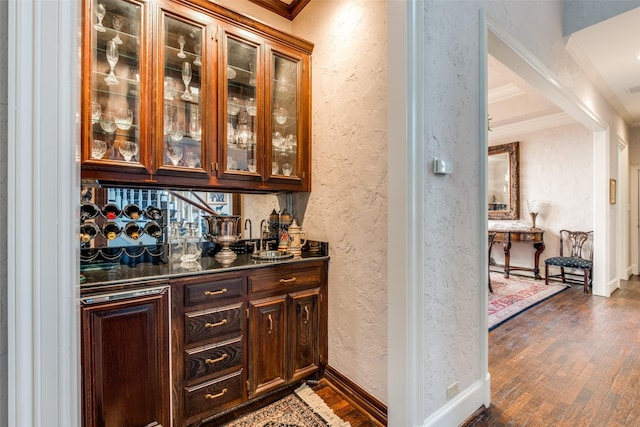 bar with dark brown cabinets, dark wood-type flooring, and ornamental molding