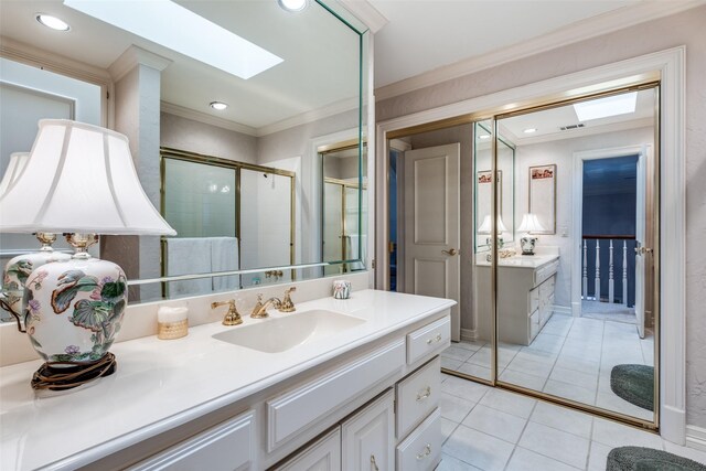 bathroom featuring a skylight, walk in shower, vanity, crown molding, and tile patterned flooring