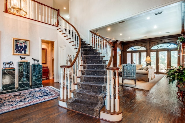 staircase featuring french doors, a high ceiling, and hardwood / wood-style floors