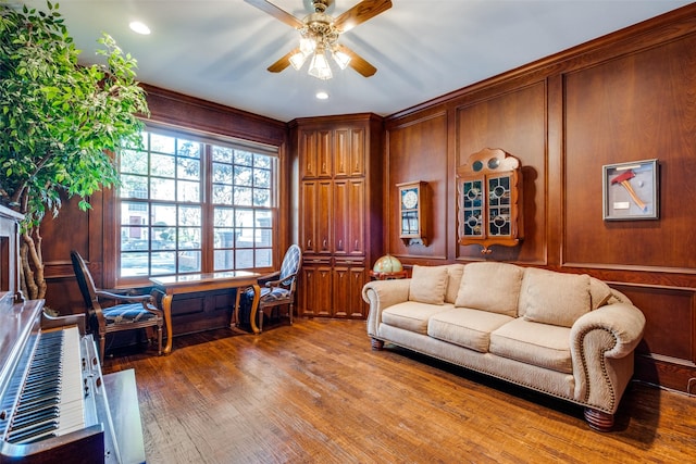 living room with ceiling fan, wooden walls, and hardwood / wood-style flooring