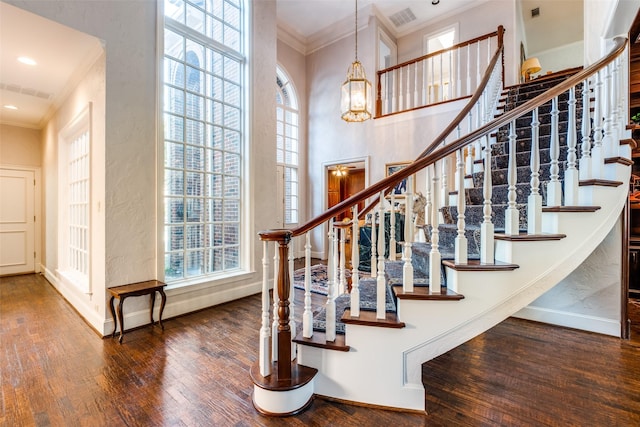 stairway featuring crown molding, a towering ceiling, and hardwood / wood-style flooring