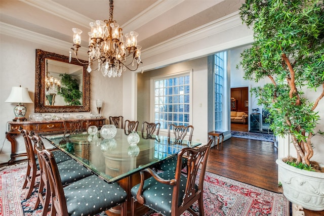 dining area with ornamental molding, dark wood-type flooring, and an inviting chandelier