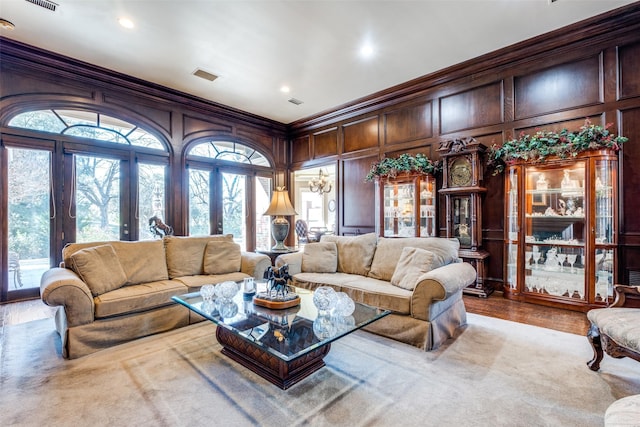 living room with wood walls, ornamental molding, and french doors