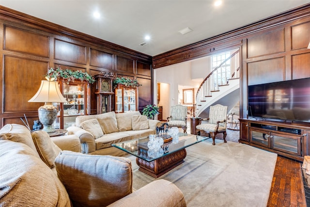 living room with hardwood / wood-style flooring, crown molding, and wood walls