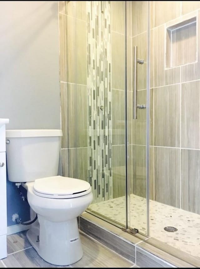 bathroom with toilet and a shower with shower door