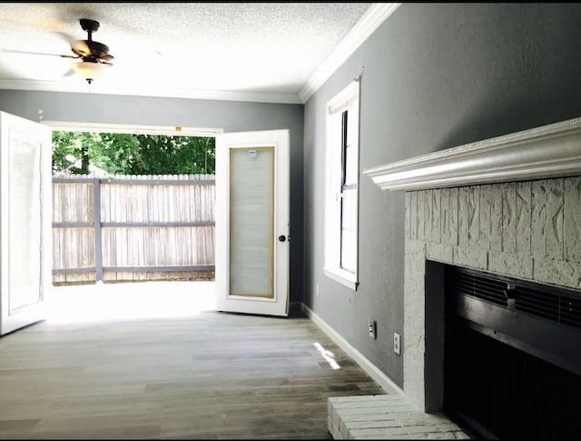 unfurnished living room featuring ceiling fan, hardwood / wood-style flooring, a textured ceiling, and ornamental molding