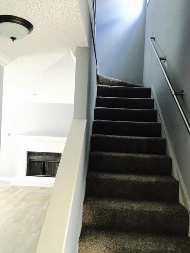 staircase featuring a textured ceiling and hardwood / wood-style flooring