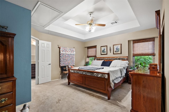 carpeted bedroom featuring ceiling fan and a tray ceiling