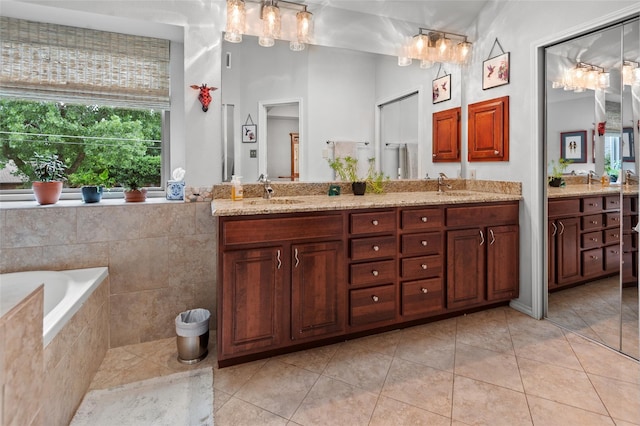 bathroom with tile patterned floors, vanity, and a relaxing tiled tub