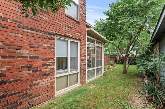 view of side of property featuring a sunroom and a yard