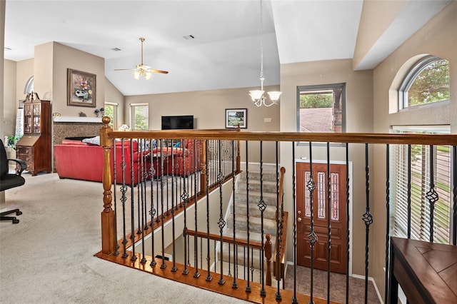 interior space with ceiling fan with notable chandelier, carpet floors, and lofted ceiling