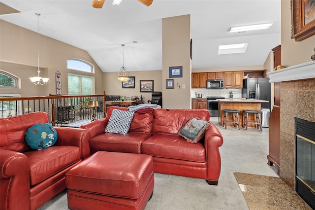 living room featuring plenty of natural light, lofted ceiling, ceiling fan with notable chandelier, and a tile fireplace