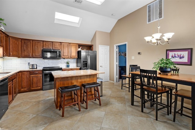 kitchen featuring tasteful backsplash, a skylight, stainless steel appliances, a chandelier, and a center island