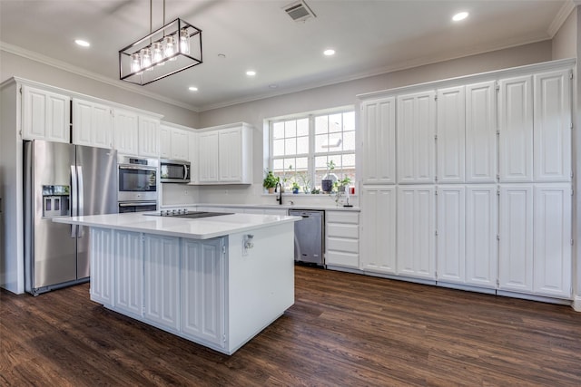 kitchen with decorative light fixtures, ornamental molding, appliances with stainless steel finishes, a kitchen island, and white cabinets