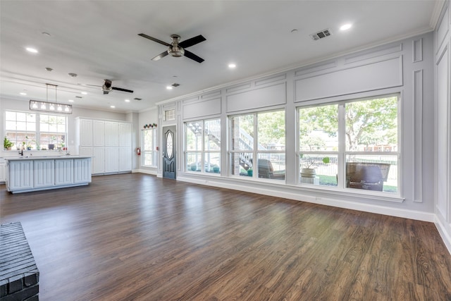 unfurnished living room featuring ornamental molding, dark wood-type flooring, and ceiling fan