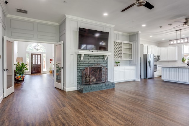 unfurnished living room with crown molding, ceiling fan, dark hardwood / wood-style floors, and a brick fireplace