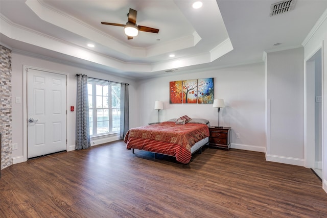 bedroom with crown molding, dark wood-type flooring, ceiling fan, and a tray ceiling