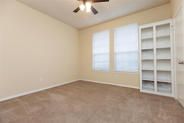 empty room with ceiling fan, light carpet, and a textured ceiling