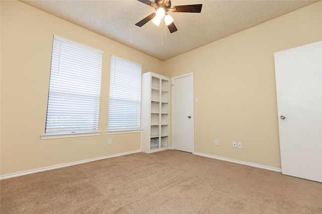 unfurnished room featuring light carpet, ceiling fan, plenty of natural light, and a textured ceiling