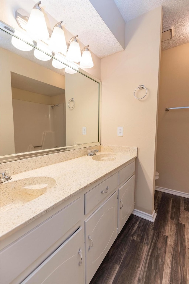 bathroom featuring hardwood / wood-style floors, vanity, a textured ceiling, toilet, and walk in shower