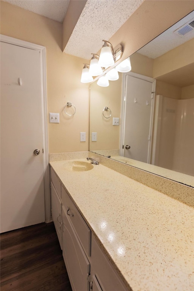 bathroom featuring vanity, wood-type flooring, and a textured ceiling