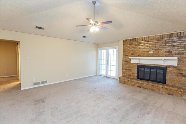 unfurnished living room featuring french doors, a brick fireplace, light carpet, a textured ceiling, and ceiling fan