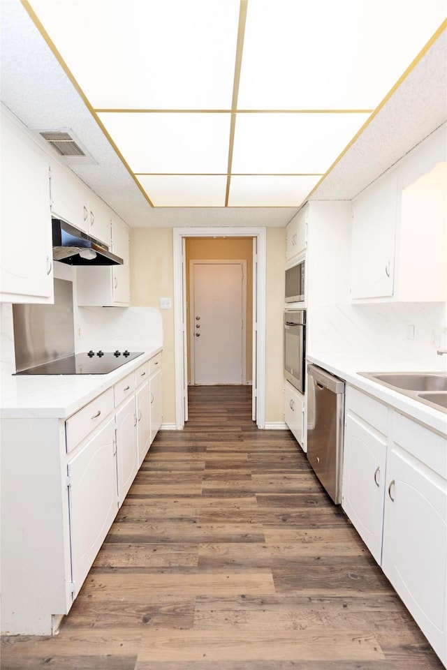 kitchen with white cabinetry, dark hardwood / wood-style flooring, stainless steel appliances, and tasteful backsplash