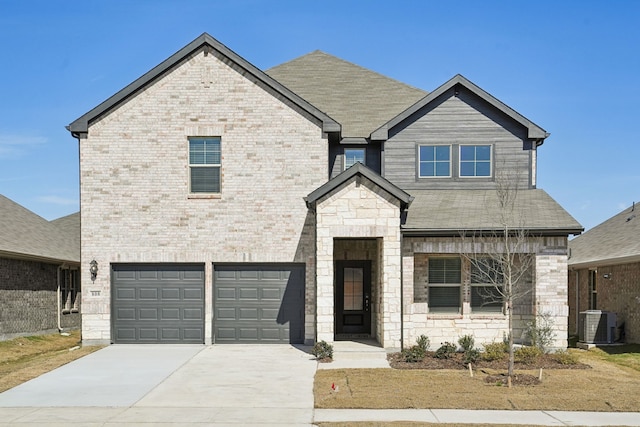 view of front of home with a garage, stone siding, central AC unit, and brick siding