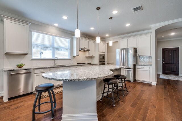 kitchen with sink, white cabinetry, hanging light fixtures, stainless steel appliances, and a kitchen island