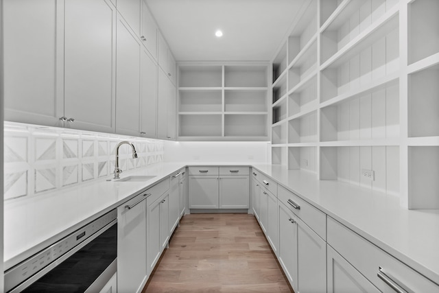 kitchen featuring dishwasher, backsplash, white cabinets, sink, and light hardwood / wood-style floors