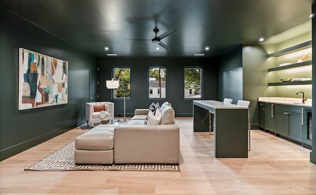 cinema with ceiling fan, sink, and light hardwood / wood-style flooring