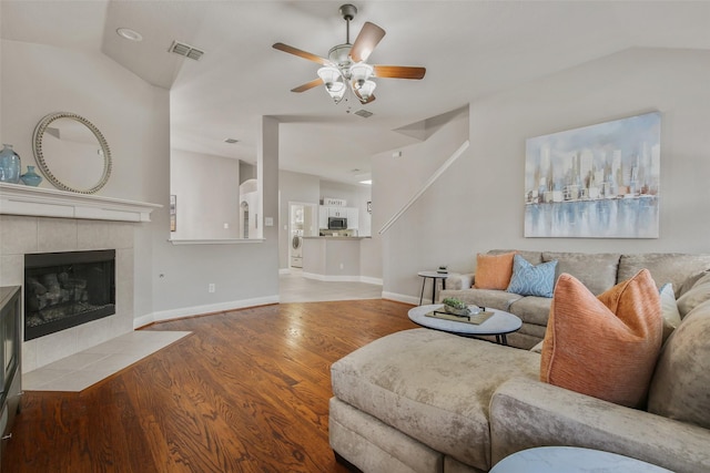 living room featuring ceiling fan, a fireplace, lofted ceiling, and light wood-type flooring