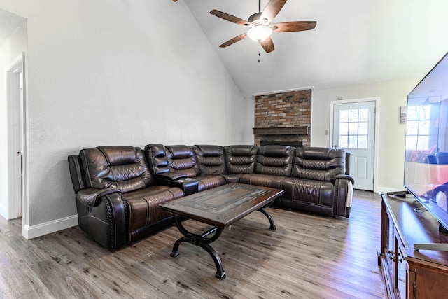 living room featuring hardwood / wood-style flooring, a fireplace, high vaulted ceiling, and ceiling fan