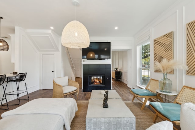 living room featuring dark hardwood / wood-style flooring, ornamental molding, and a fireplace