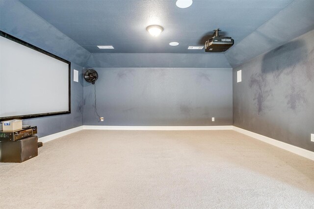 carpeted cinema room with vaulted ceiling